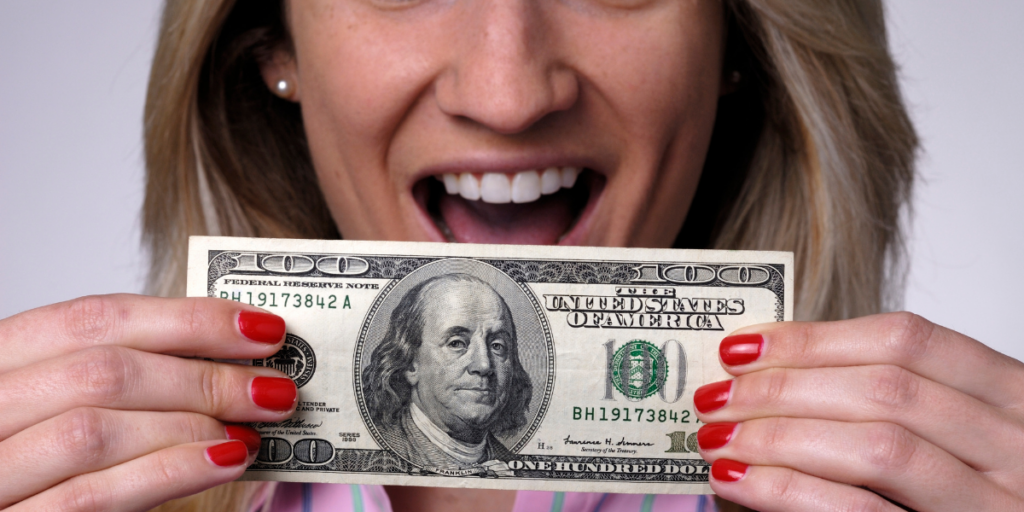 A lady holding a hundred dollar bill received as a cash back offer in place of a gift card. 