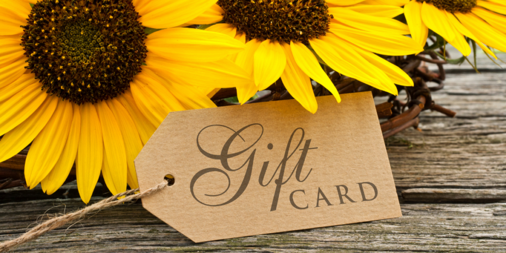A gift card tag laying by sunflowers.