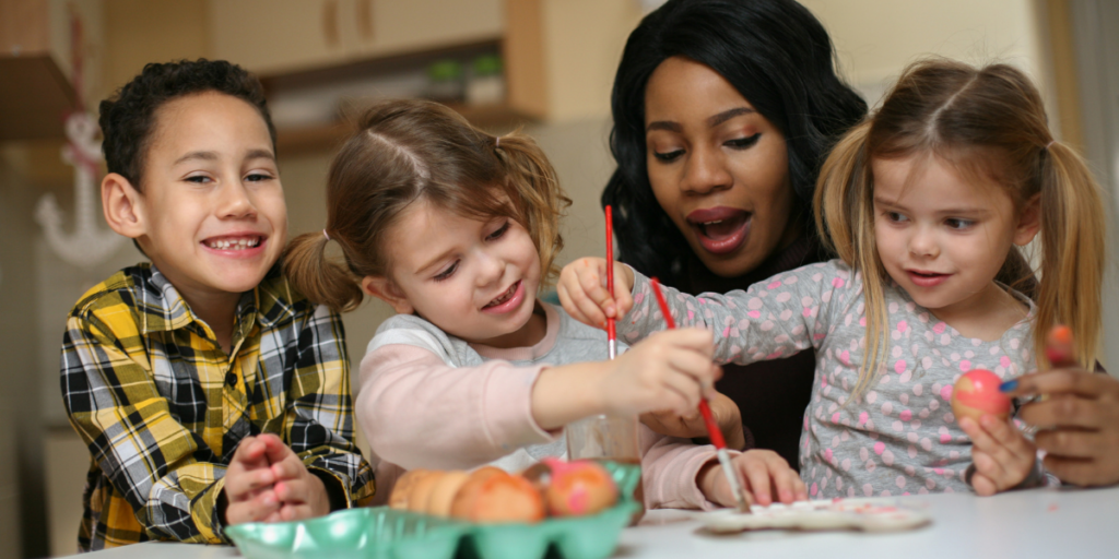 A woman helping kids paint eggs while working part time as a nanny. 