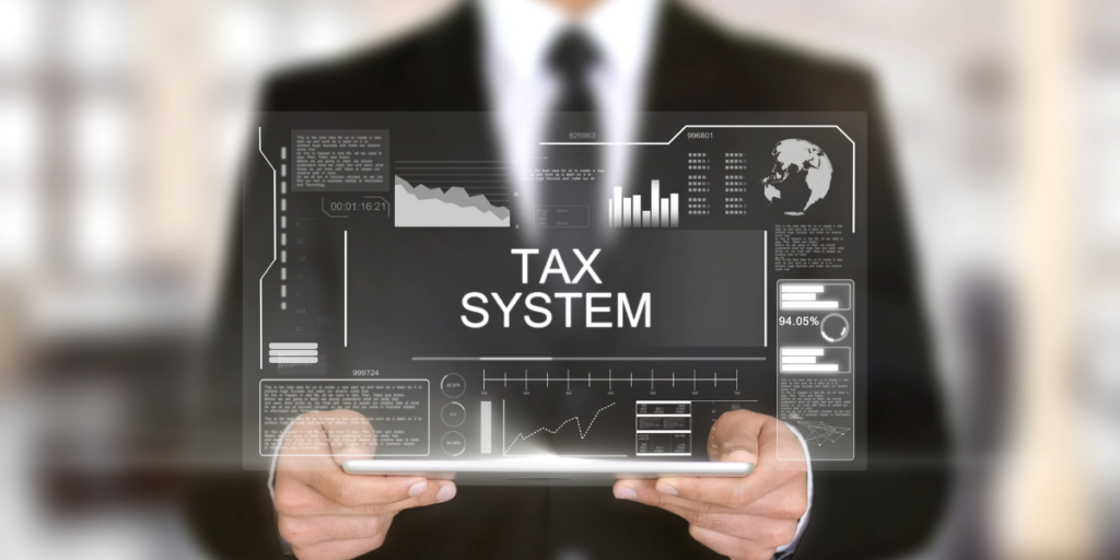 A man displaying a computer image with the words tax system in the middle of the screen. 