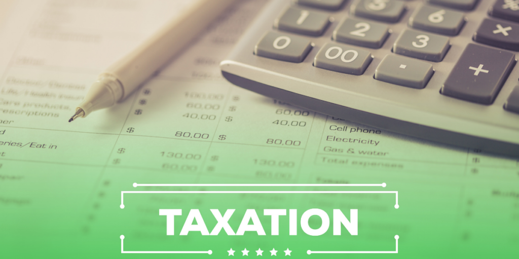 The word taxation in front of a calculator, pen and a budget form with budget amounts and taxes listed. 