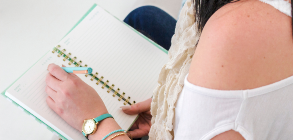 Woman budgeting on a blue notebook using a blue pen