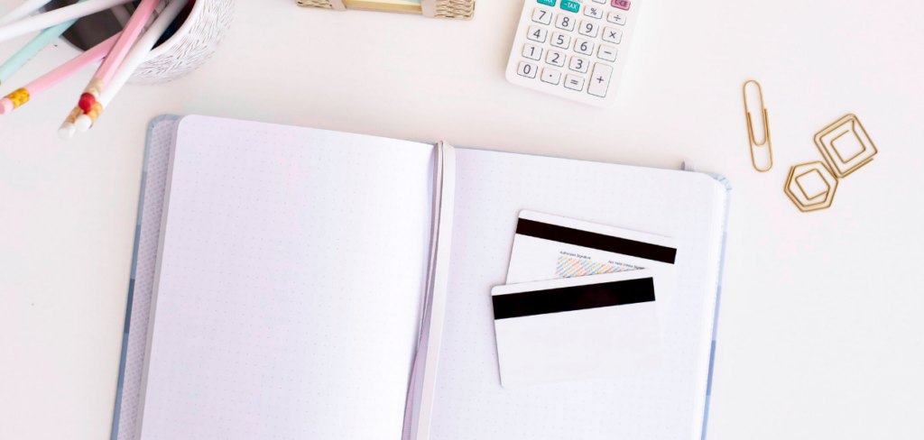 Credit cards on top of a notebook with calculator and pencils on the side