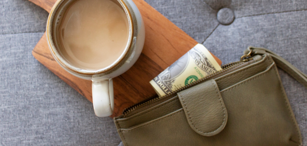 A cup of coffee beside a purse with money