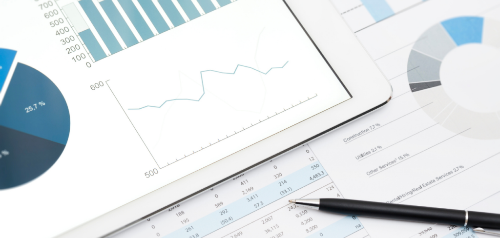 a tablet displaying charts beside a black pen