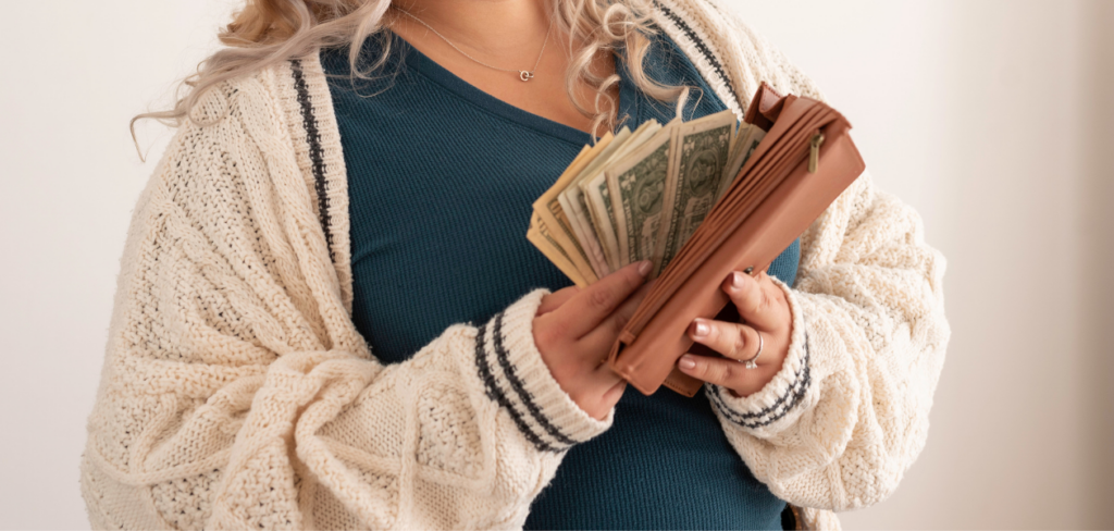 A woman holding a brown wallet and counting money to invest in dividend growth stocks