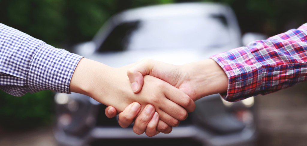 Shaking hands with a car in the background