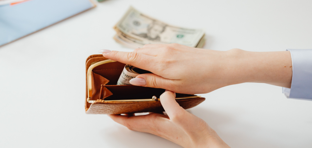 A person putting money in a brown wallet