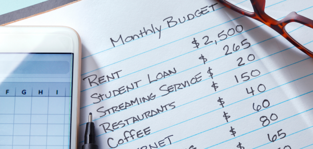 A list of monthly budget expenses, a cellphone, pen, and eyeglasses