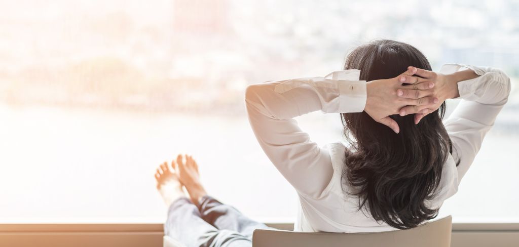 Woman sitting in chair feet propped up looking out window.