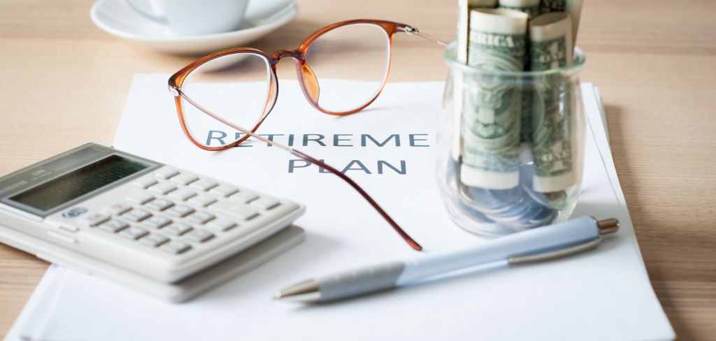 Eye glasses, calculator and pen.  Money in a small jar and a retirement plan book.