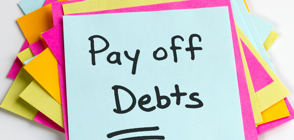 Post it notes pink, yellow, blue with the words Pay Off Debt written in black marker.