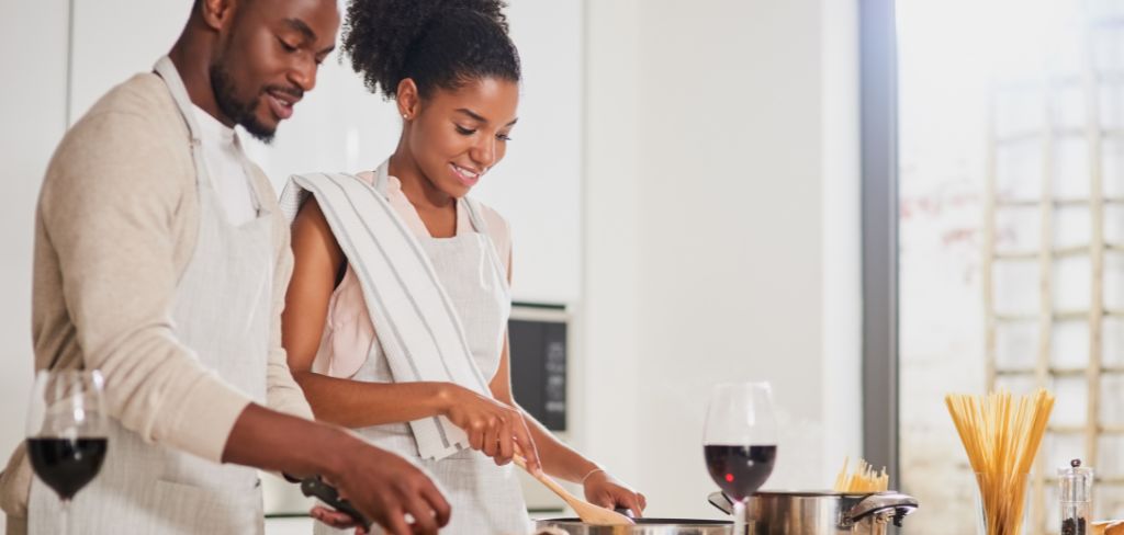 Couple cooking pasta together having a glass of wine.