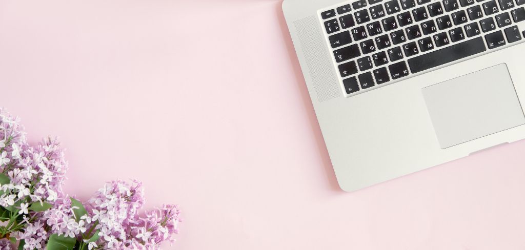 Laptop keyboard with purple flowers on pink background.