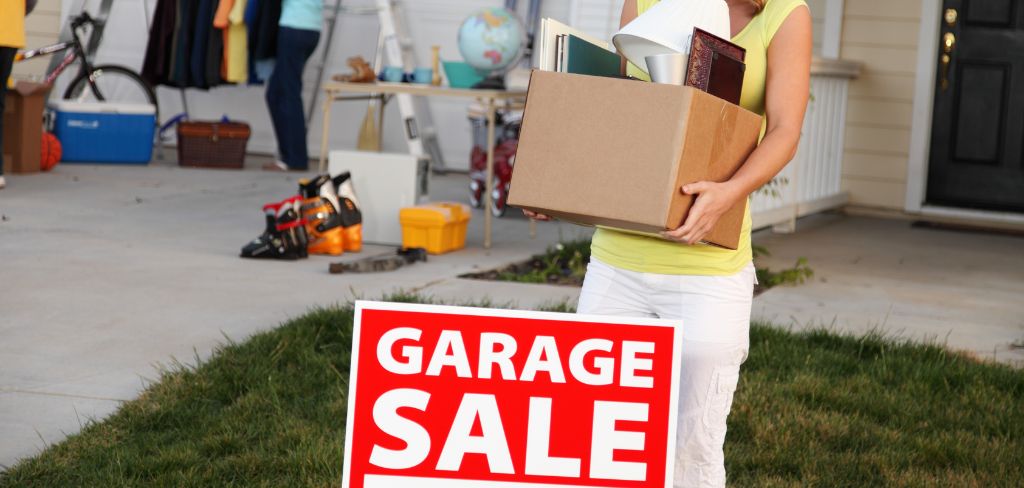 Garage sale sign, woman carrying a box of household items.