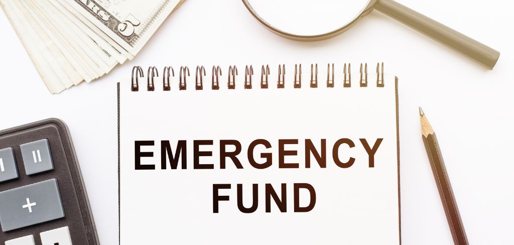Calculator, pencil, money and pad with the words Emergency Fund.