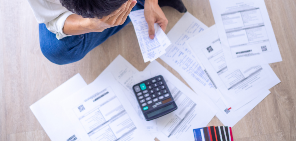 Man stressed about financial problems. With invoices and various bills and calculators placed around him.