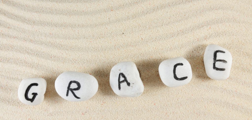 Grace word on group of stones with sand background.