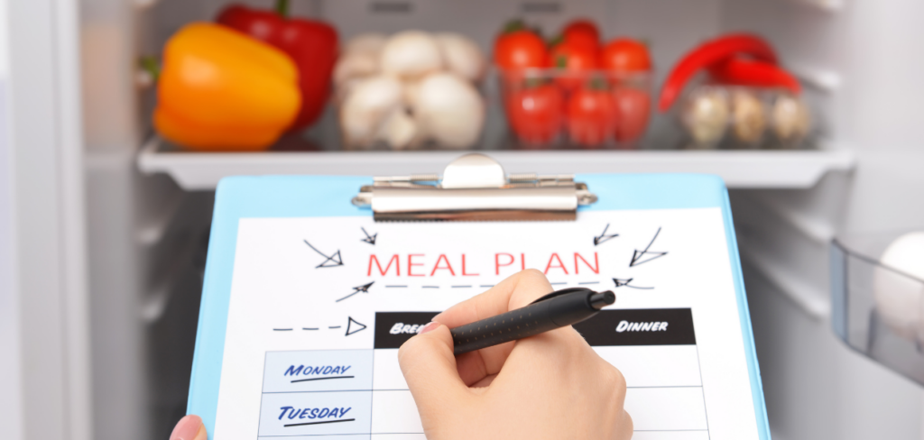 A woman making meal plan in front of a refrigerator.