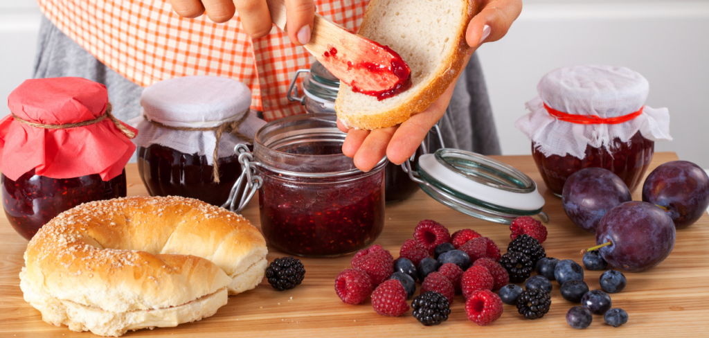 A woman spreading the bread with jam for breakfast.