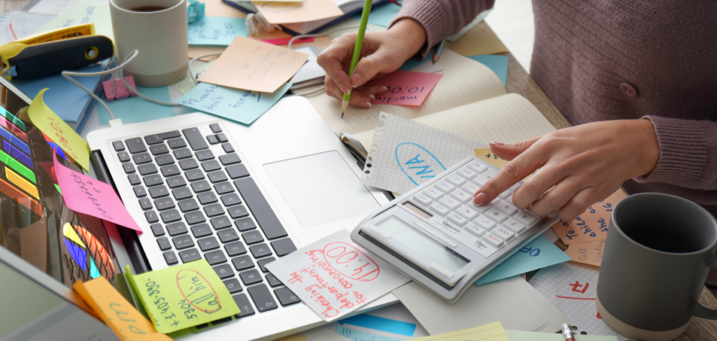 Overwhelmed woman working at a messy office desk. 