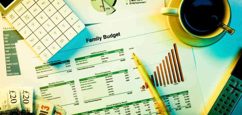 A family budget, calculator, coffee, money, and pen on a desk.