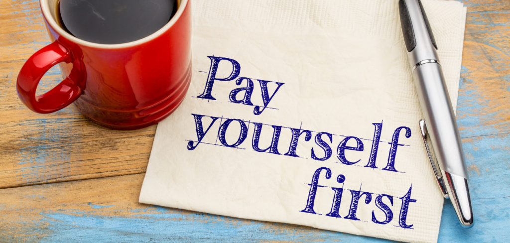 Pay yourself first handwritten on a napkin with cup of coffee.