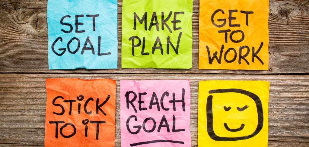 Set goal, make plan, work, stick to it, reach goal written on a colorful sticky notes.