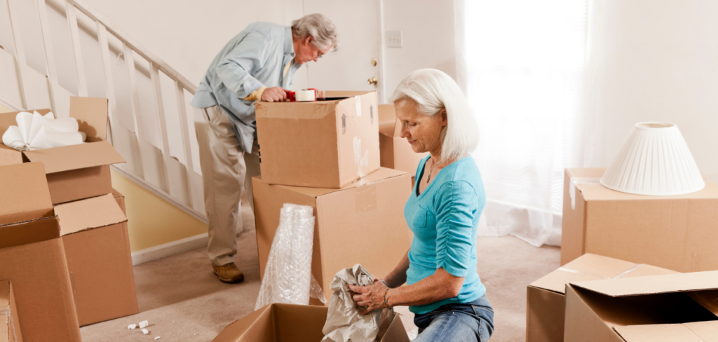 A senior couple packing boxes inside a house.