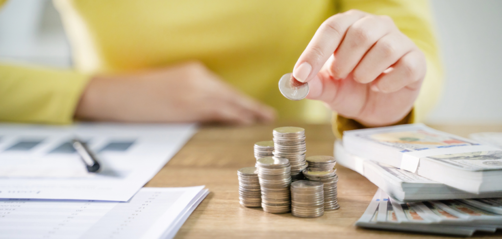 Pen, paper, coins, and money are on the table to plan for the 2024 Savings Challenge.