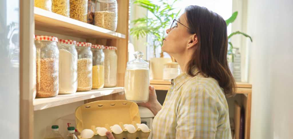 Woman in pantry taking eggs and grain products in storage jars.