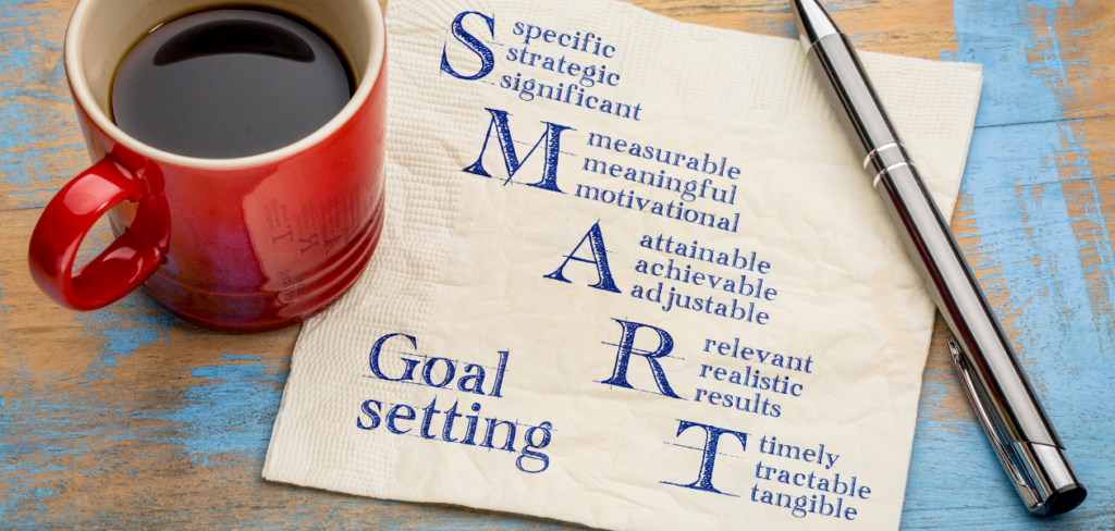 A napkin with the word SMART written on it next to a cup of coffee and a pen.