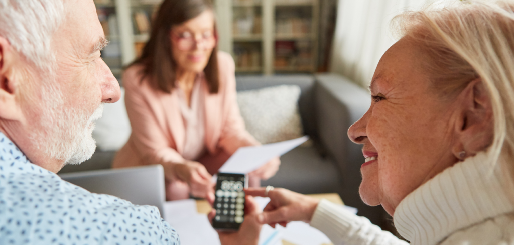 Happy senior couple calculating retirement savings with financial advisor at home.