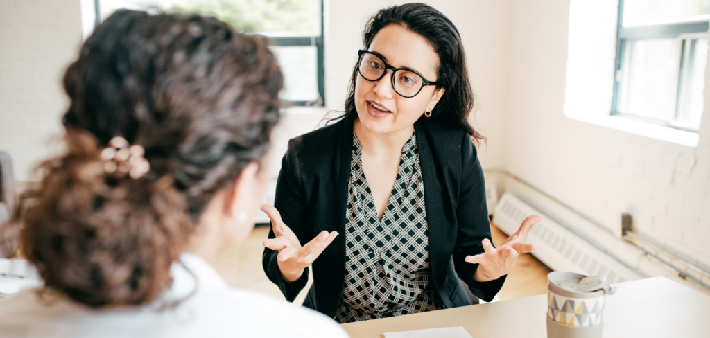 A woman sitting at a table giving financial advice to another person.