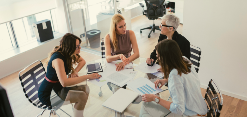 A group of women sitting around a table having a meeting.