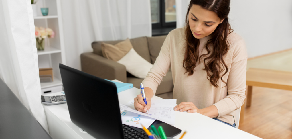 A woman sitting at a desk with a laptop and pen learning at home.