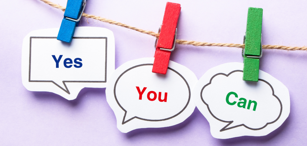 Speech bubbles with the words "Yes You Can" written on them are attached to a line using wooden clips, with a purple background.
