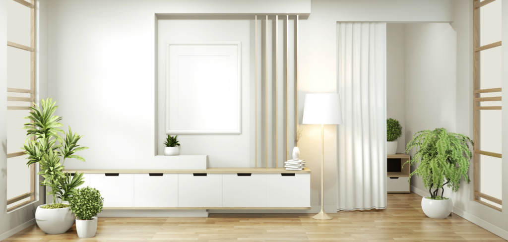 A minimalist living room with white walls, plants wooden floors.
