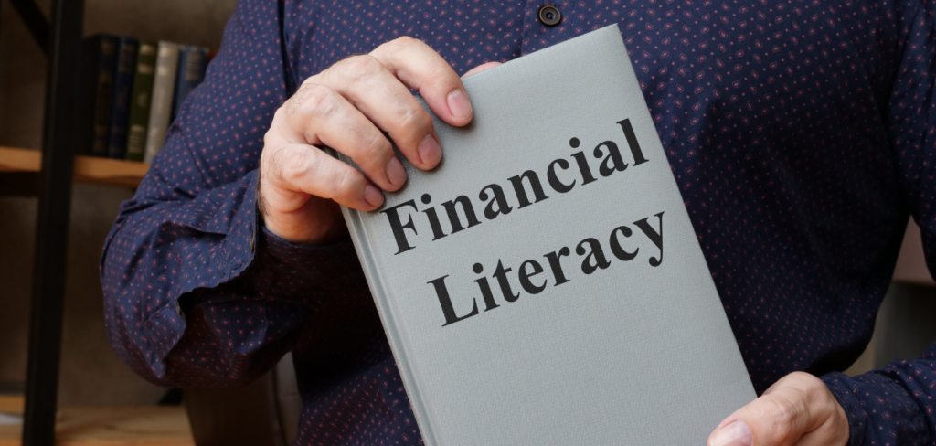A man is holding a book about financial literacy.
