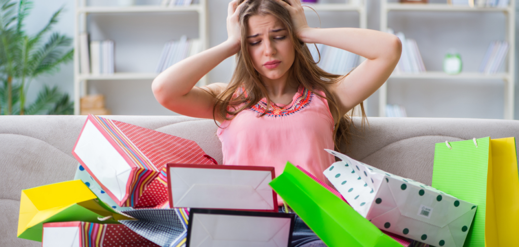 A frustrated young woman sitting on a couch at home with a lot of shopping bags
