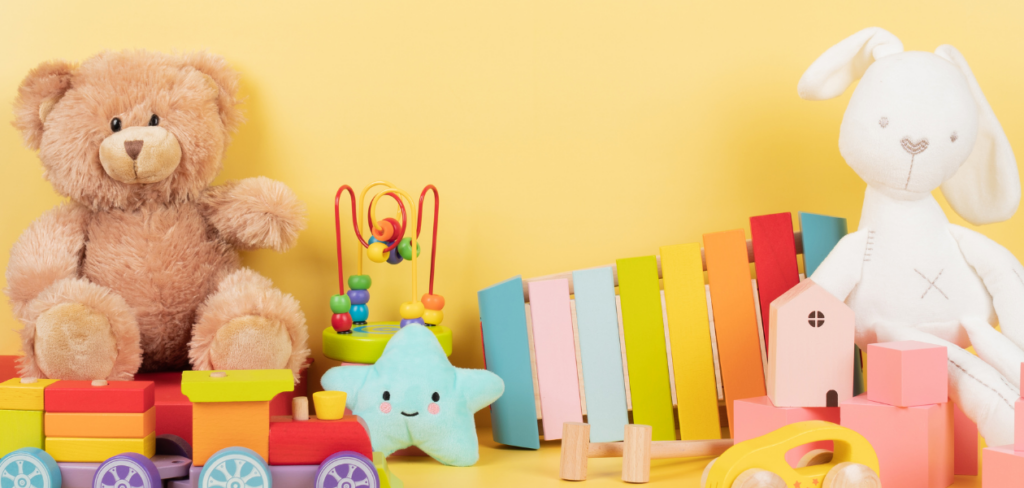 Stuffed animals, a toy train, xylophone, and colorful puzzle pieces on a yellow background.
