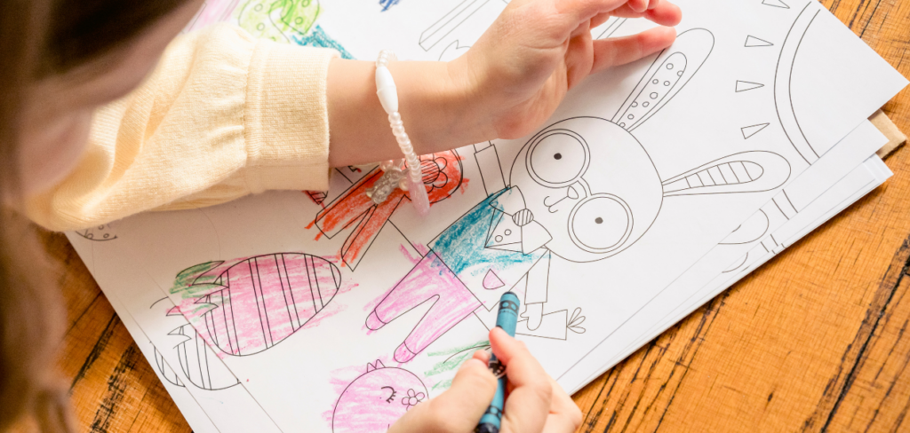 A girl is coloring a page in a coloring book.