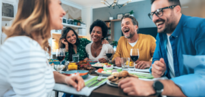 A group of friends gathered around a dining table, laughing and enjoying a meal together.