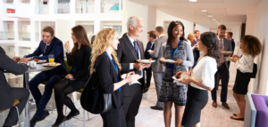 Group of professionals networking and socializing at a business event, enjoying refreshments and engaging in conversations in a modern venue.