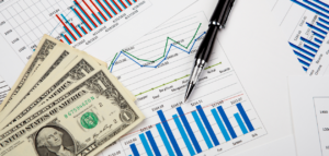 Charts with dollar bills and a pen, representing finances and budgeting.