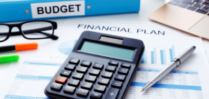Close-up of a financial planning workspace with a calculator, budget binder, financial charts, and graphs.