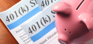 A pink piggy bank sits on top of 401(k) documents.