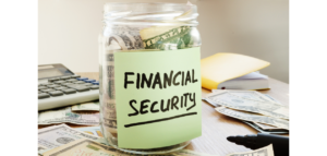 A glass jar filled with cash and labeled "FINANCIAL SECURITY" sits on a desk with other money, a calculator, and a notepad.