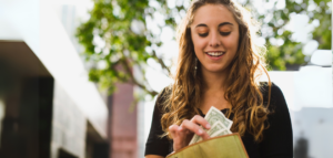 A young woman smiles as she takes out some US dollar bills from her purse.