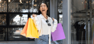 A woman laughs happily as she carries several colorful shopping bags.